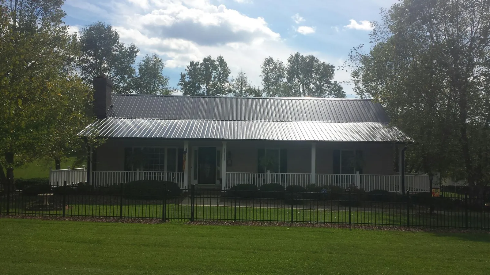 Gray metal roof on a brick ranch with a full width front porch — Gutter Guard Installation work by our crew in Paxtonville