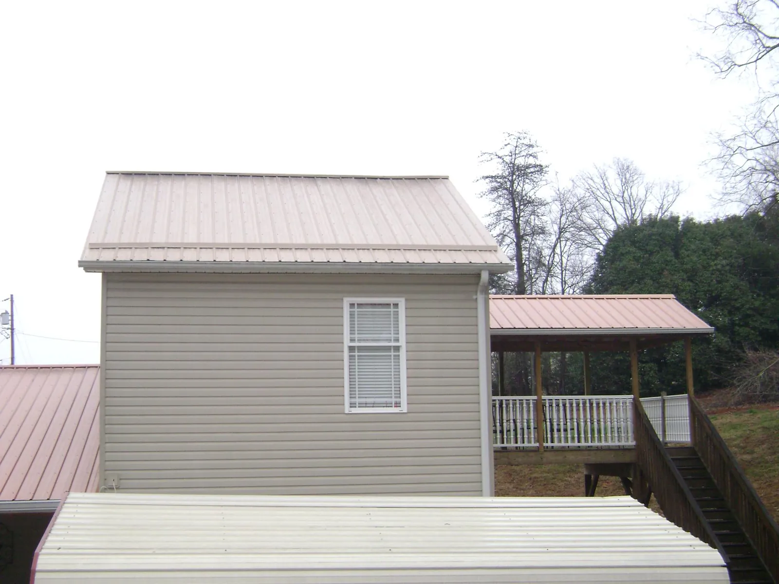 Tan metal roofs on a two story addition and attached porch, from a Roof Replacement job in Paxtonville
