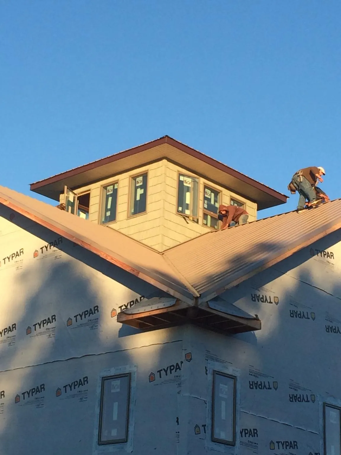 Roofers working around a rooftop cupola on a new metal roof at sunset — Roof Waterproofing in Paxtonville by Roofing Brothers